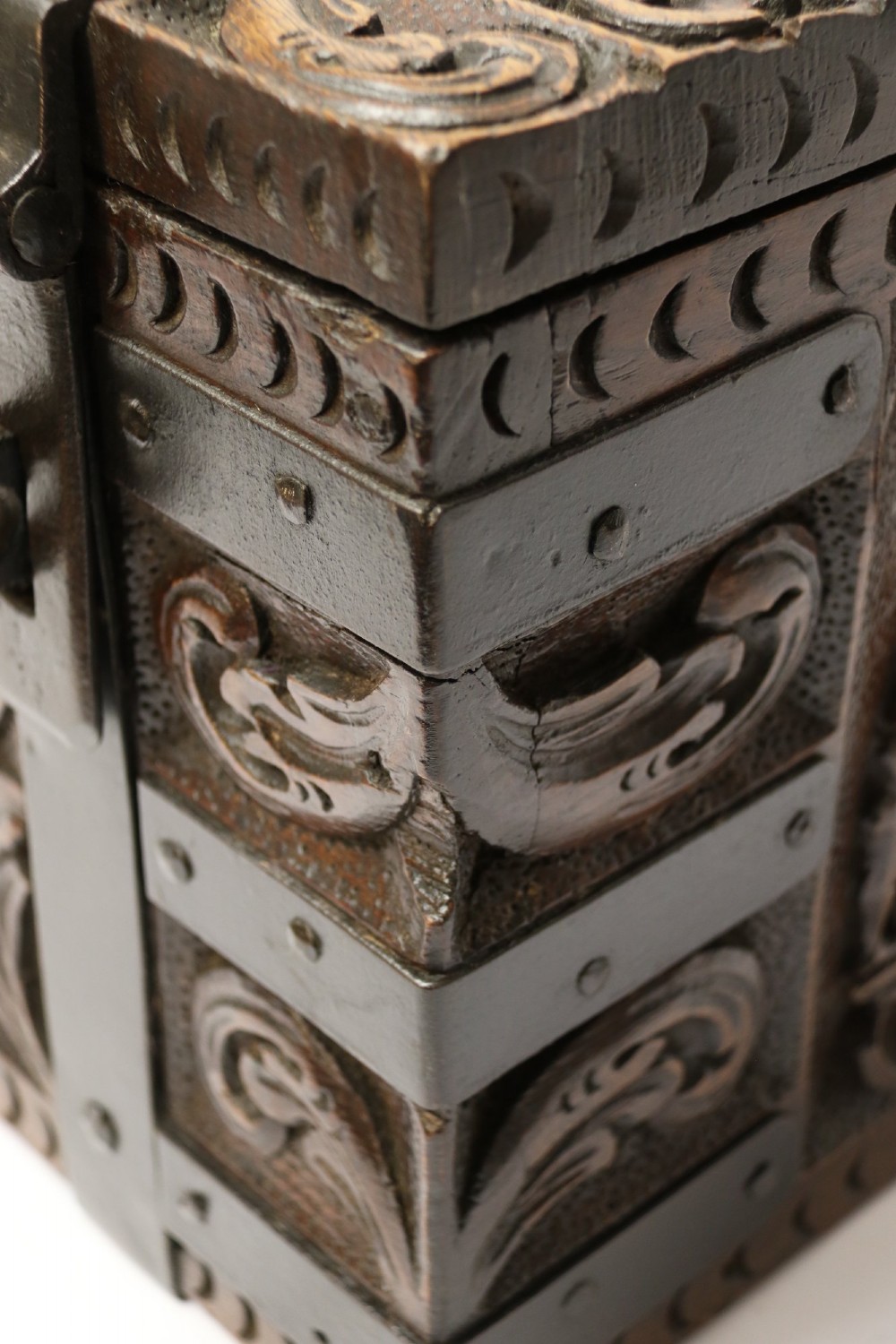 A dark carved oak strong box featuring metal binding straps, side drop handles, and relief carvings of figures and foliage. View IV