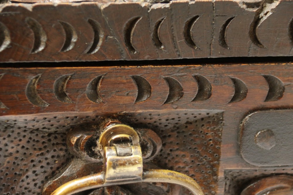 A dark carved oak strong box featuring metal binding straps, side drop handles, and relief carvings of figures and foliage. View VII