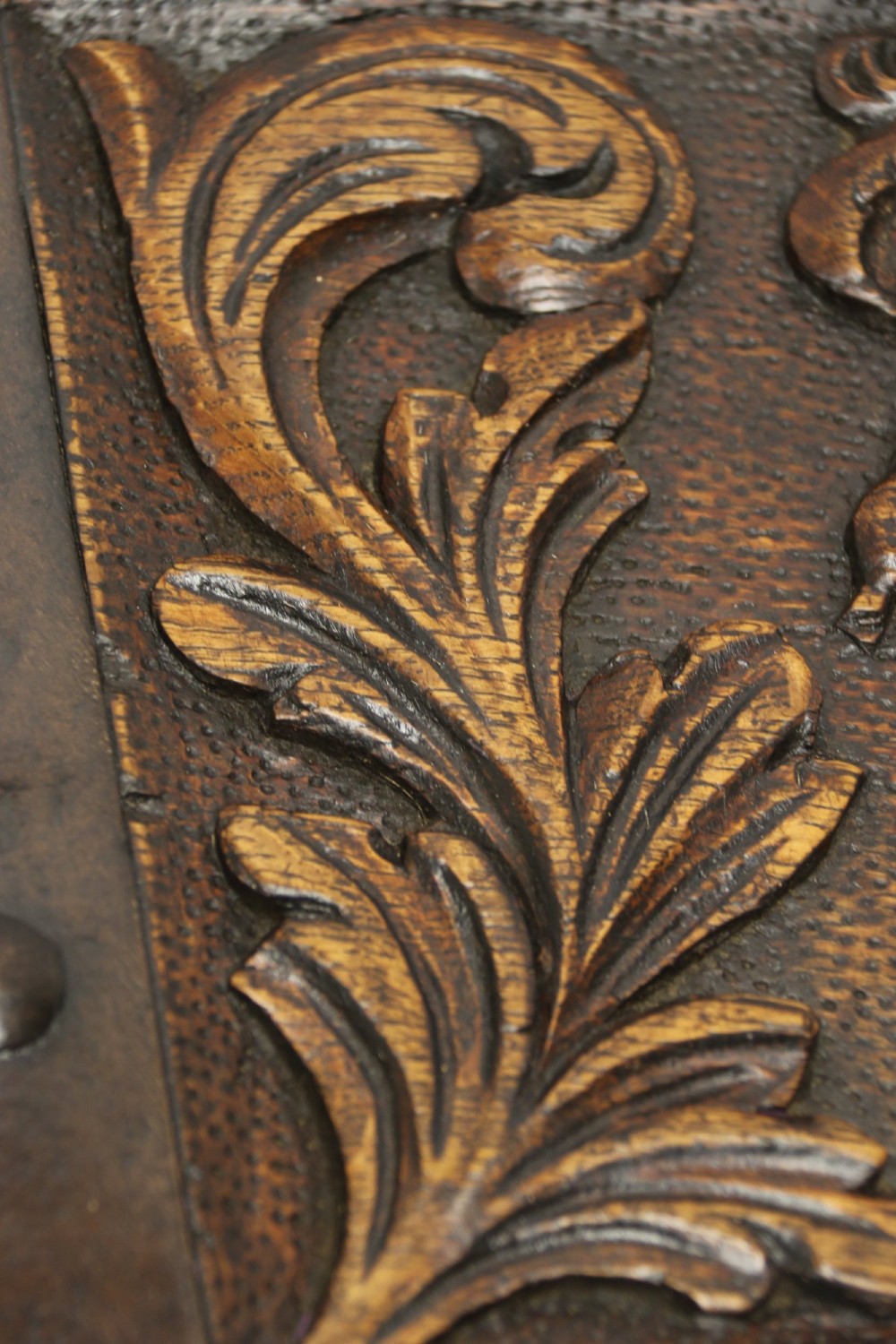 A dark carved oak strong box featuring metal binding straps, side drop handles, and relief carvings of figures and foliage. View XIII