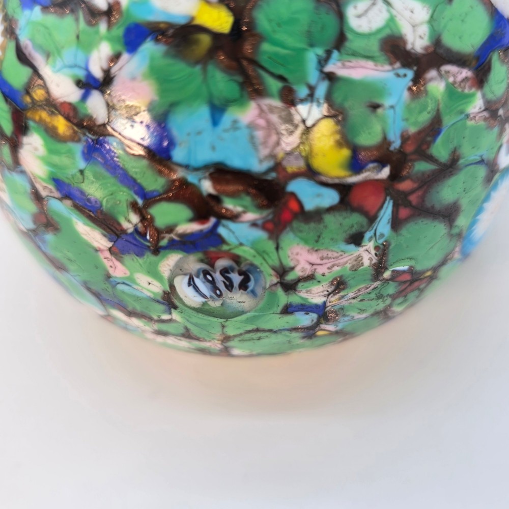A spherical Murano glass paperweight featuring multicoloured millefiori cane patterns embedded within a vibrant green field. View II