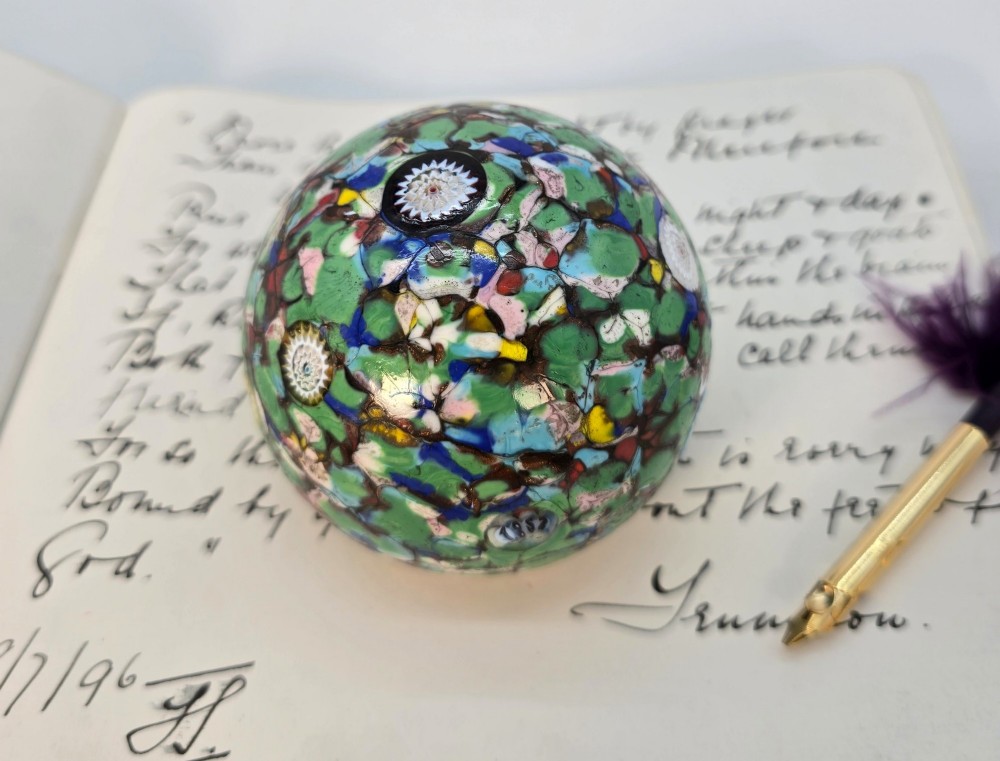 A spherical Murano glass paperweight featuring multicoloured millefiori cane patterns embedded within a vibrant green field. View IV