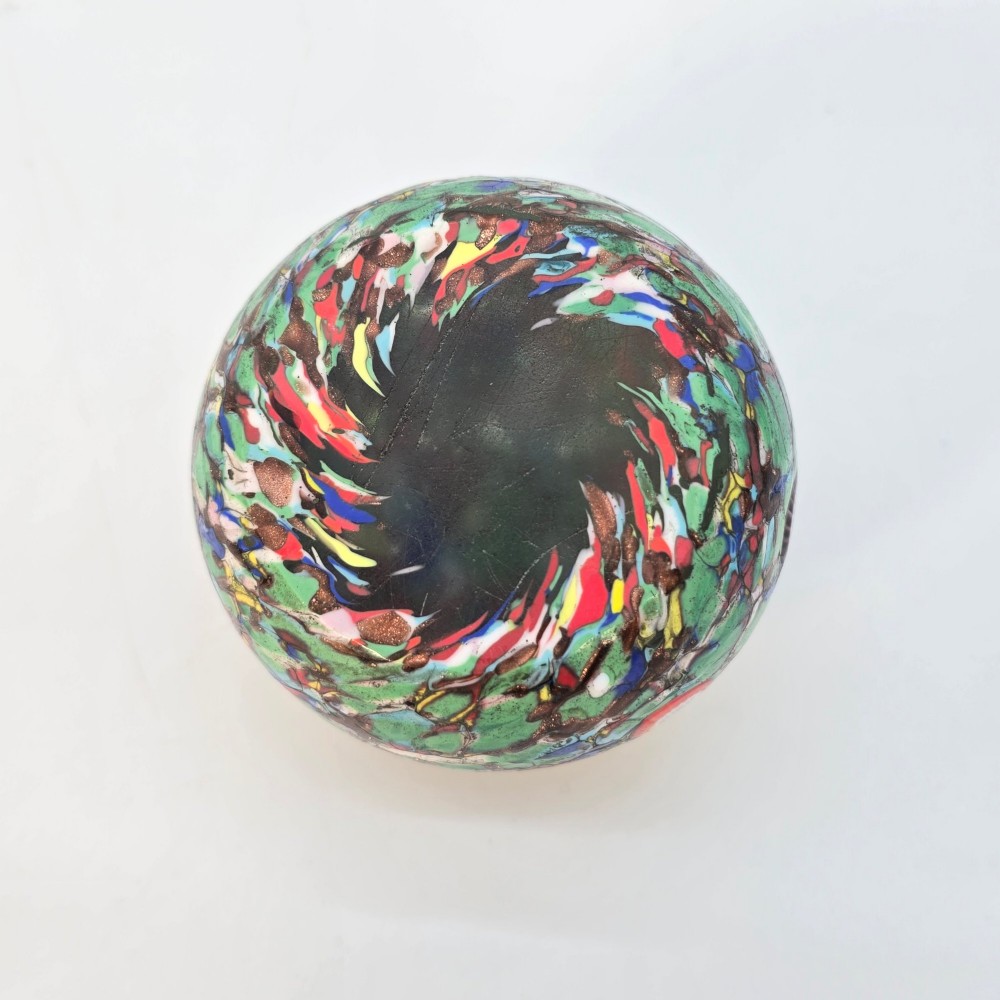 A spherical Murano glass paperweight featuring multicoloured millefiori cane patterns embedded within a vibrant green field. View VIII