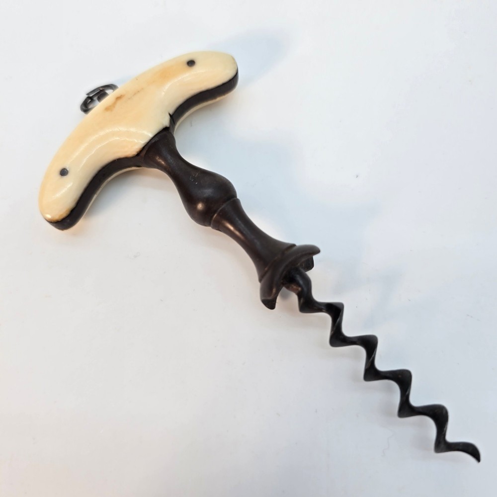 An early nineteenth-century corkscrew featuring a curved cream-coloured bone handle and a turned dark wood shaft with a steel helix.