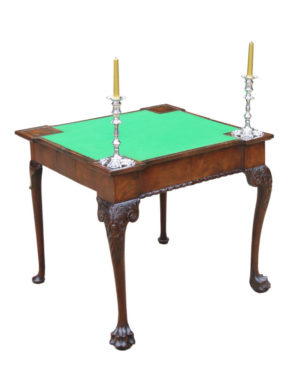 An 18th-century mahogany fold-out card table with a green baize inset top, corner candle stands, and carved cabriole legs ending in claw and ball feet.
