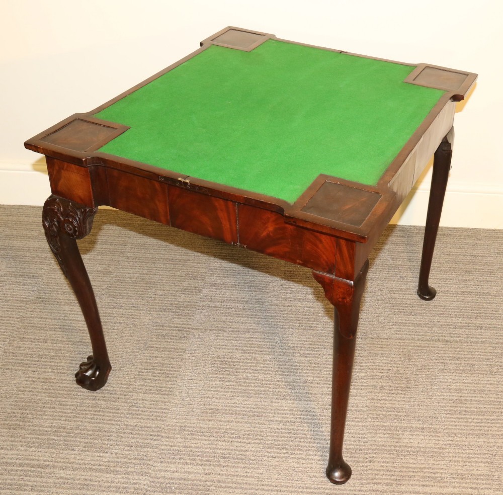 An 18th-century mahogany fold-out card table with a green baize inset top, corner candle stands, and carved cabriole legs ending in claw and ball feet. View V