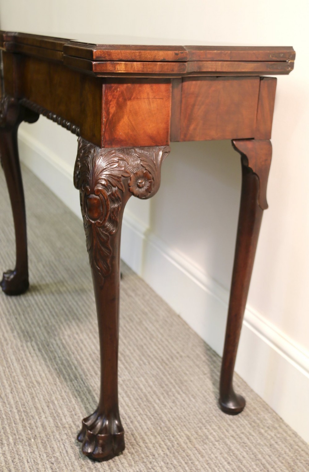 An 18th-century mahogany fold-out card table with a green baize inset top, corner candle stands, and carved cabriole legs ending in claw and ball feet. View IX