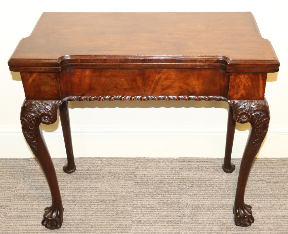 An 18th-century mahogany fold-out card table with a green baize inset top, corner candle stands, and carved cabriole legs ending in claw and ball feet. View XIII