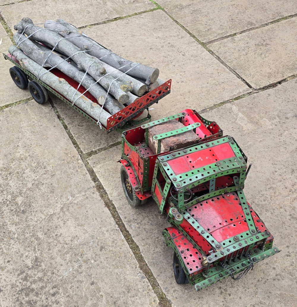 A detailed 1930s red and green Meccano model truck with a loaded timber trailer. View IV