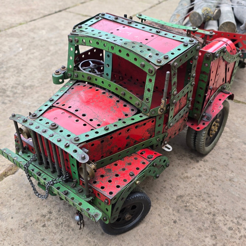 A detailed 1930s red and green Meccano model truck with a loaded timber trailer. View V