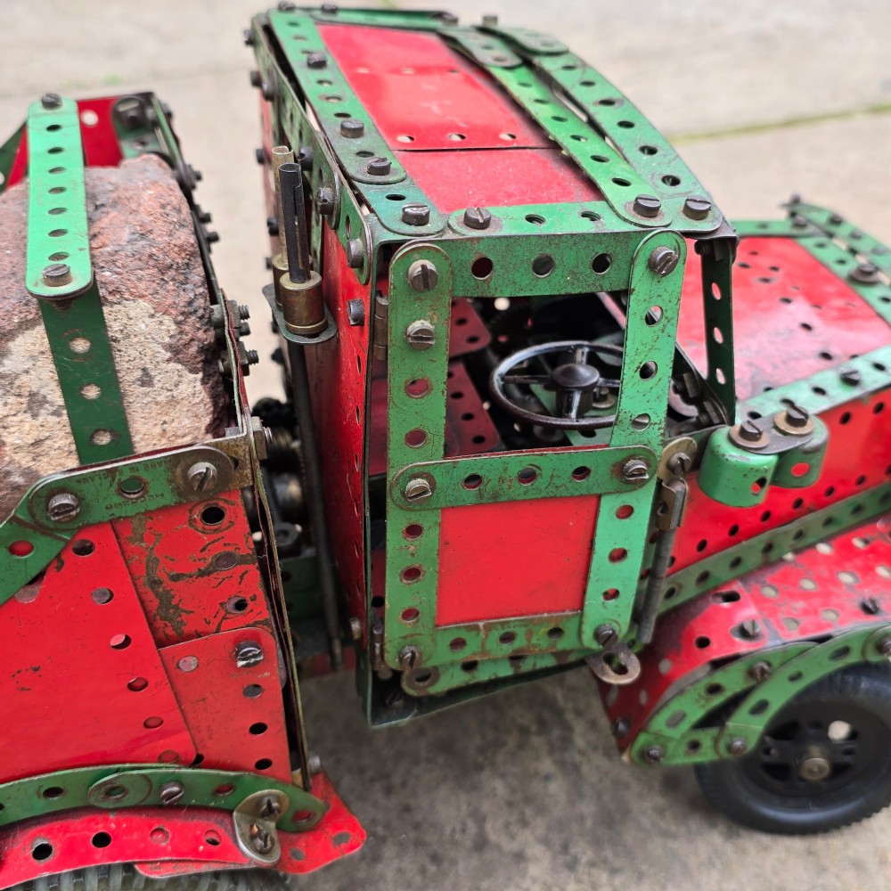 A detailed 1930s red and green Meccano model truck with a loaded timber trailer. View VI