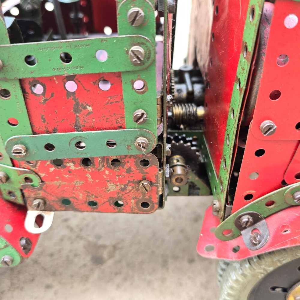 A detailed 1930s red and green Meccano model truck with a loaded timber trailer. View VIII