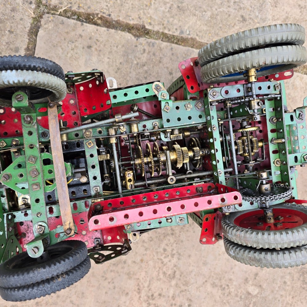 A detailed 1930s red and green Meccano model truck with a loaded timber trailer. View X