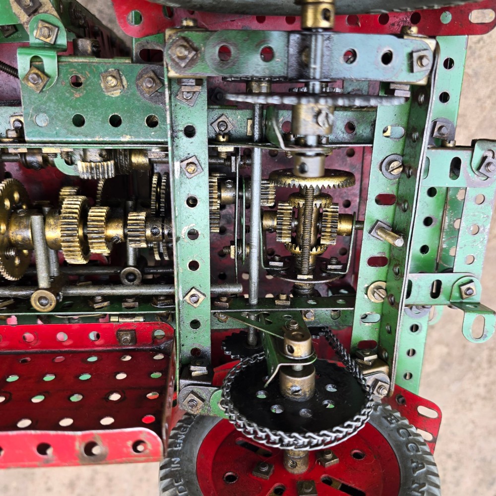 A detailed 1930s red and green Meccano model truck with a loaded timber trailer. View XI