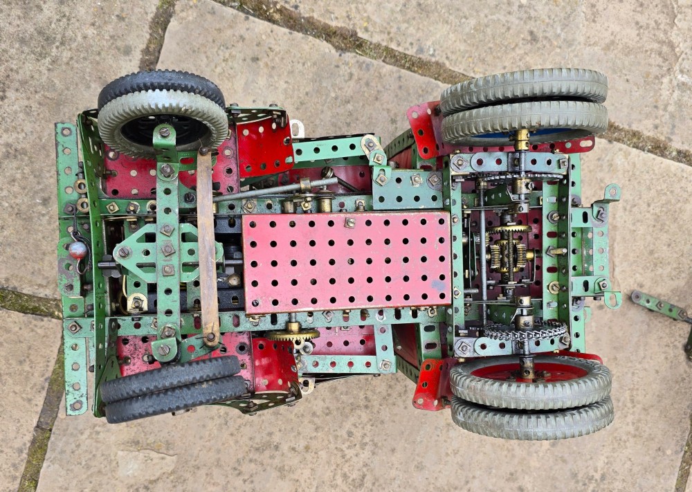 A detailed 1930s red and green Meccano model truck with a loaded timber trailer. View XII