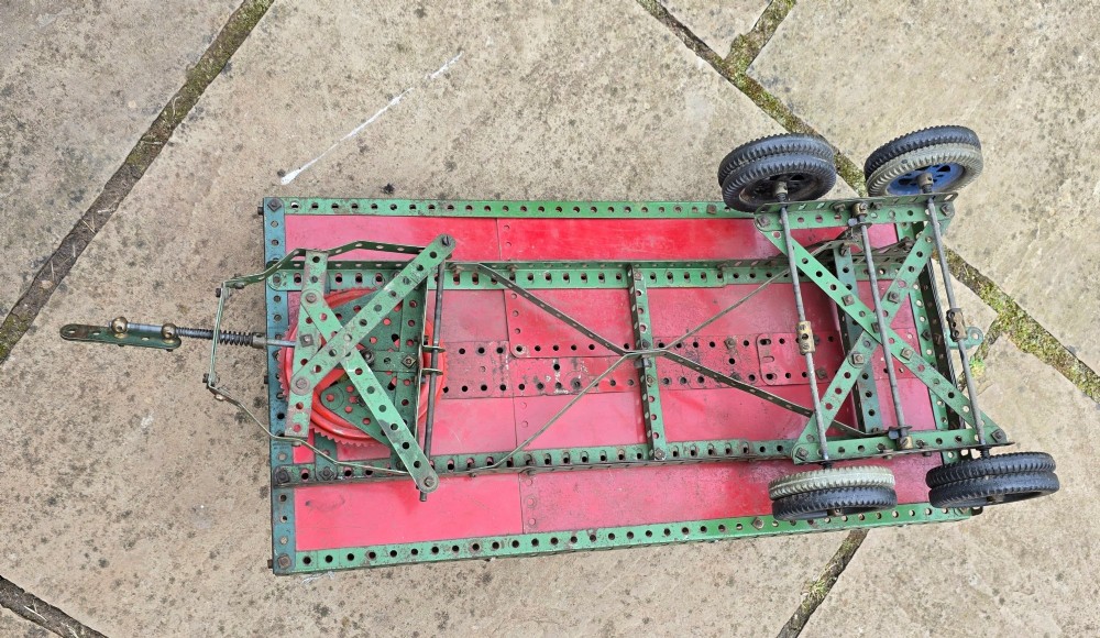 A detailed 1930s red and green Meccano model truck with a loaded timber trailer. View XIV