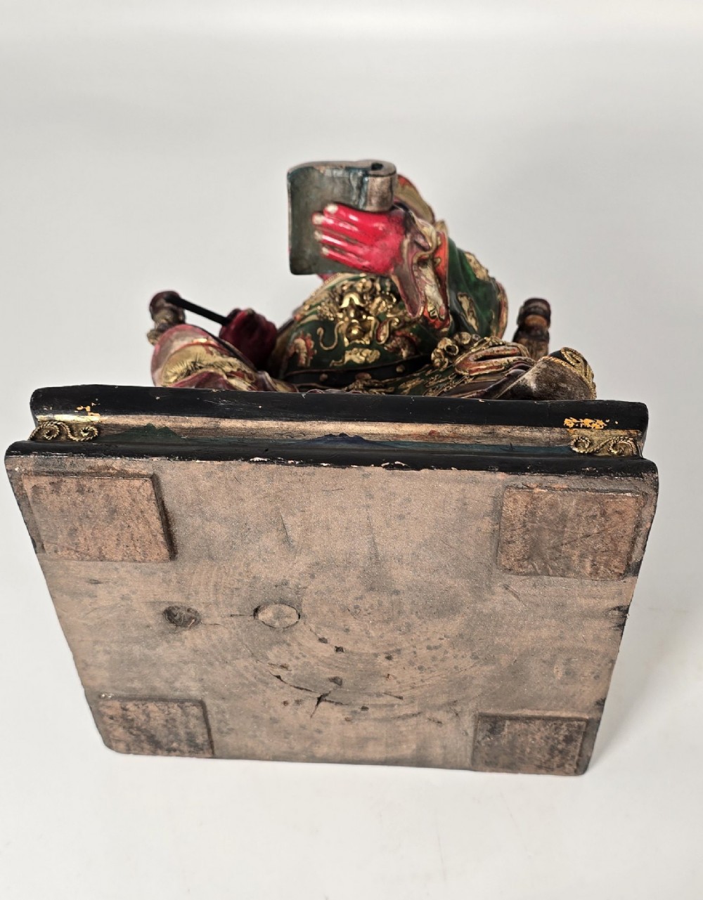 A carved Chinese lacquered wooden figure seated on a throne, rendered in bright red, green, and gold paint with intricate details. View XI