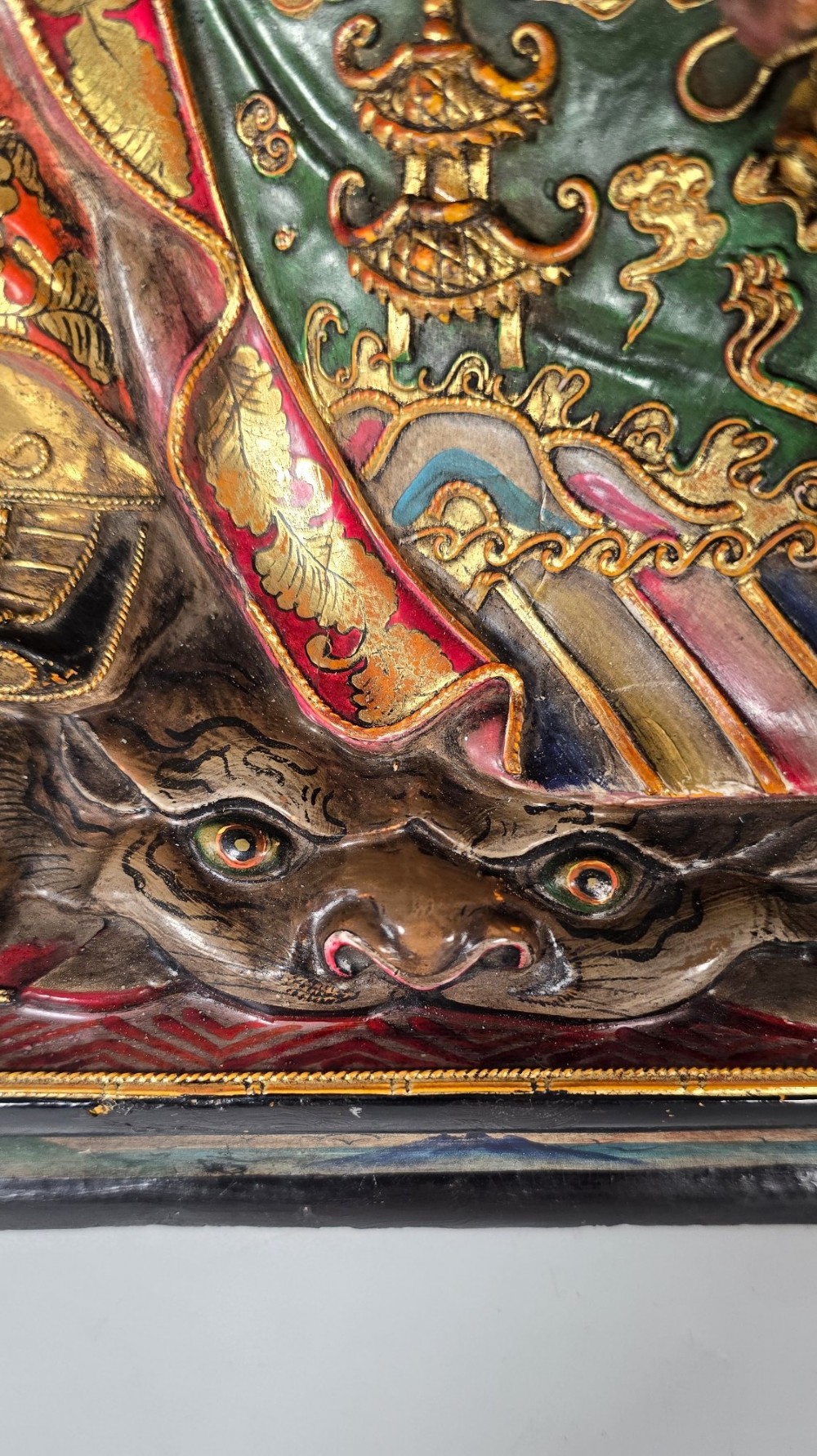 A carved Chinese lacquered wooden figure seated on a throne, rendered in bright red, green, and gold paint with intricate details. View XII