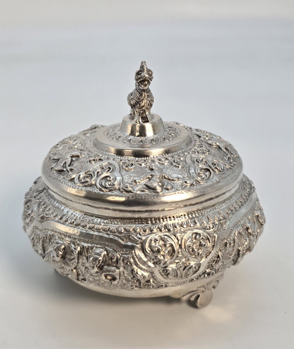 A circular Anglo-Indian chased silver jar featuring ornate scrollwork detailing and a small animal finial on the lid. View IV