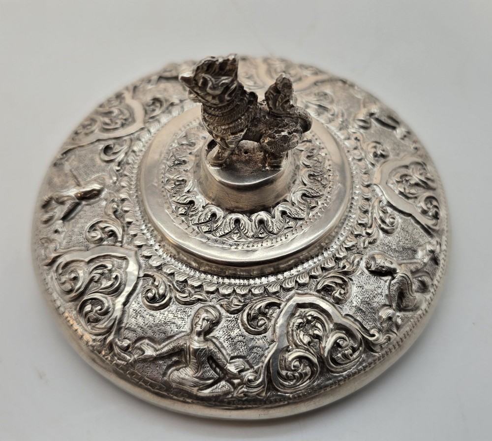 A circular Anglo-Indian chased silver jar featuring ornate scrollwork detailing and a small animal finial on the lid. View VII