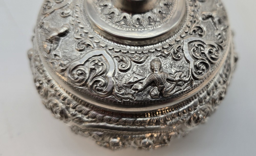 A circular Anglo-Indian chased silver jar featuring ornate scrollwork detailing and a small animal finial on the lid. View X