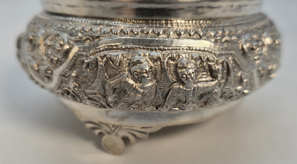A circular Anglo-Indian chased silver jar featuring ornate scrollwork detailing and a small animal finial on the lid. View XI