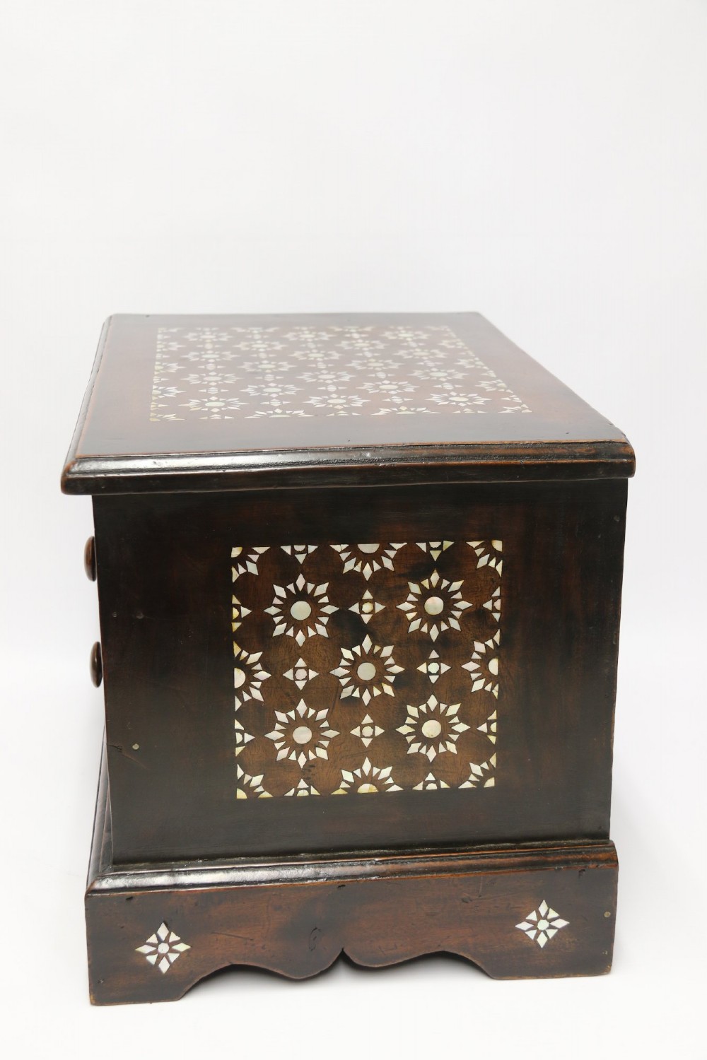 A dark hardwood tabletop chest featuring three drawers decorated with geometric bone inlay and turned wooden knobs. View II