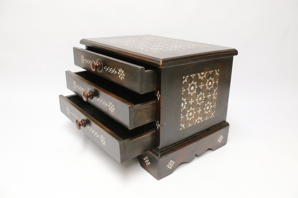 A dark hardwood tabletop chest featuring three drawers decorated with geometric bone inlay and turned wooden knobs. View III