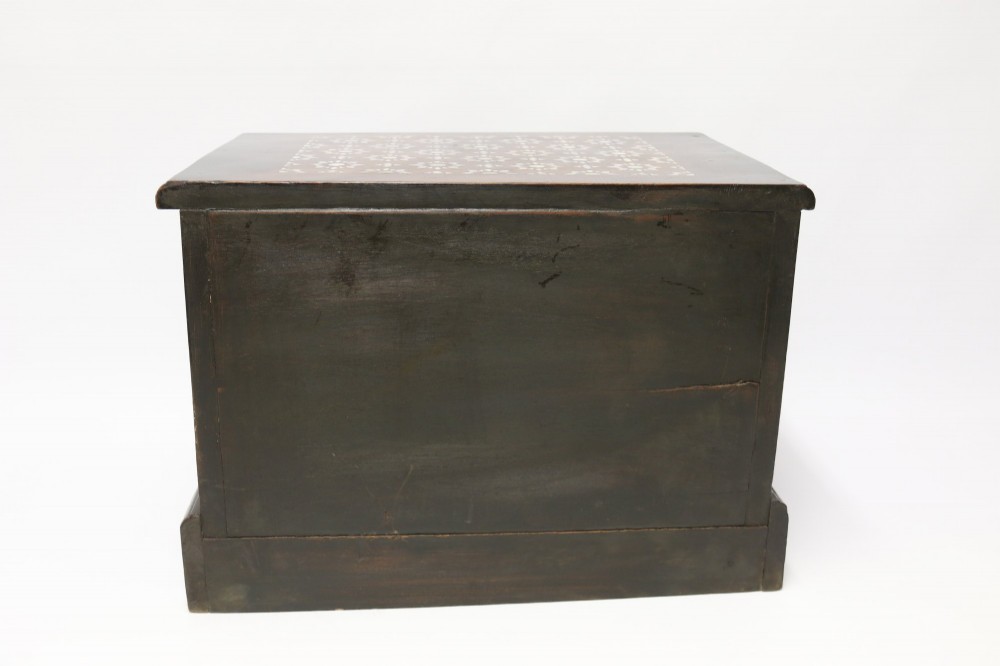 A dark hardwood tabletop chest featuring three drawers decorated with geometric bone inlay and turned wooden knobs. View VI