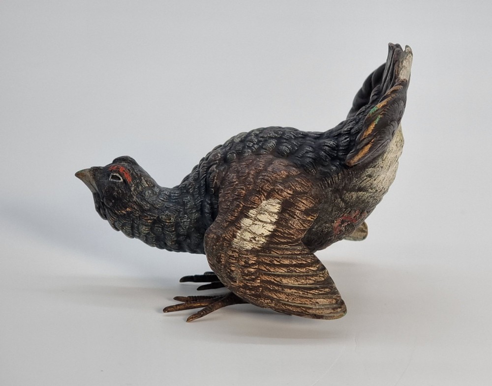 A cold painted bronze sculpture depicting a capercaillie in a display pose with textured dark brown feathers and red eye accents. View II