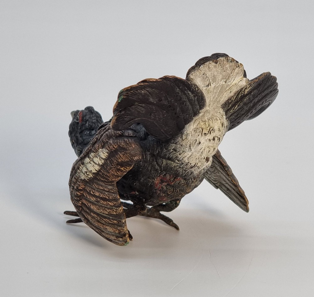 A cold painted bronze sculpture depicting a capercaillie in a display pose with textured dark brown feathers and red eye accents. View III