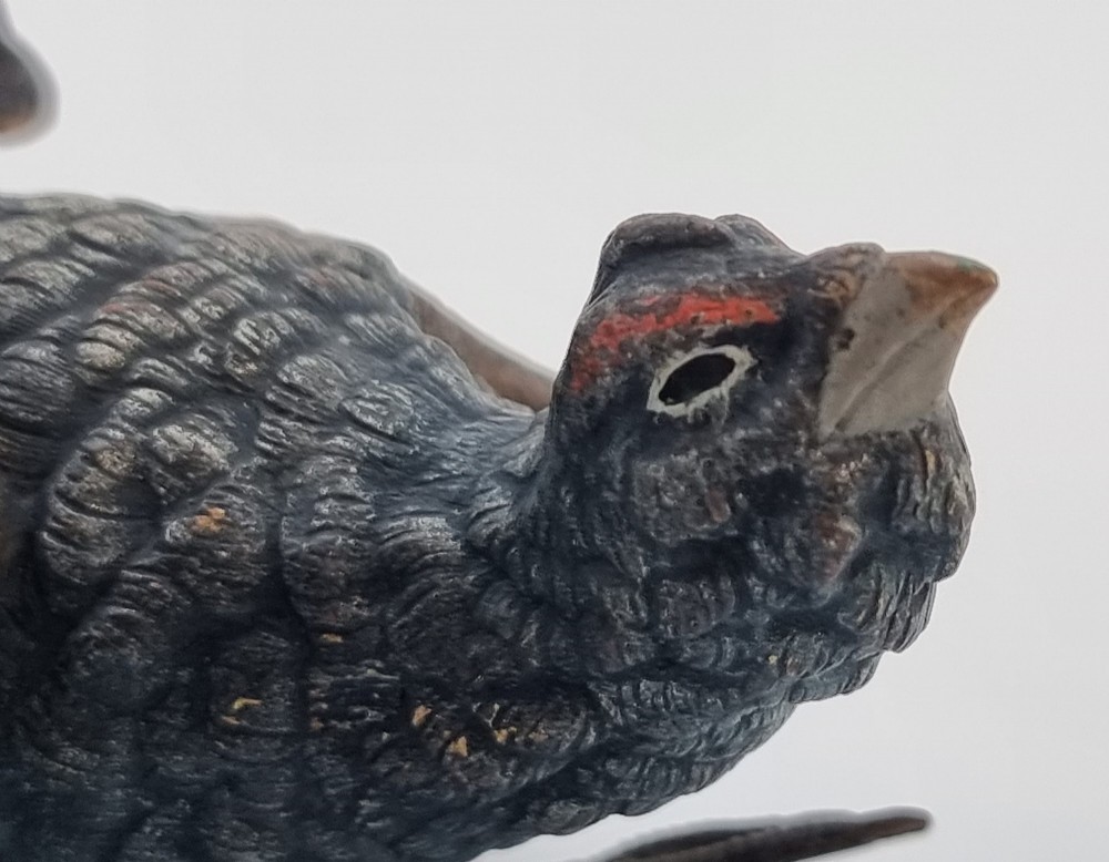 A cold painted bronze sculpture depicting a capercaillie in a display pose with textured dark brown feathers and red eye accents. View VII