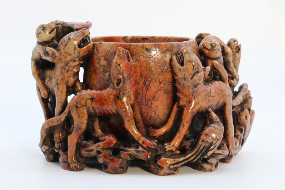 A cylindrical reddish-brown carved soapstone brush pot featuring sculpted animal figures in high relief surrounding an engraved vessel. View II