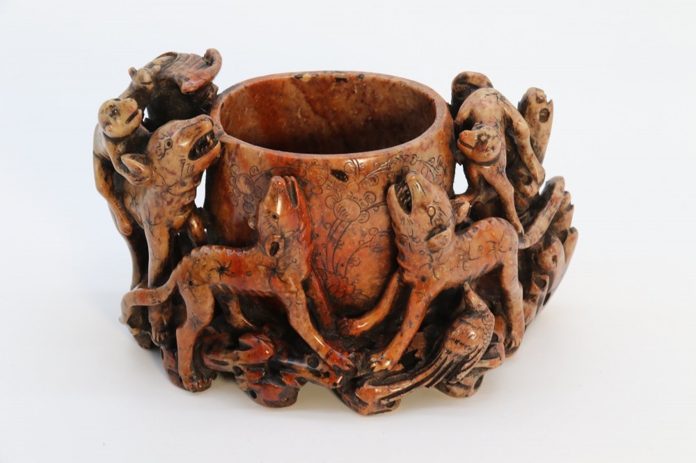 A cylindrical reddish-brown carved soapstone brush pot featuring sculpted animal figures in high relief surrounding an engraved vessel. View III