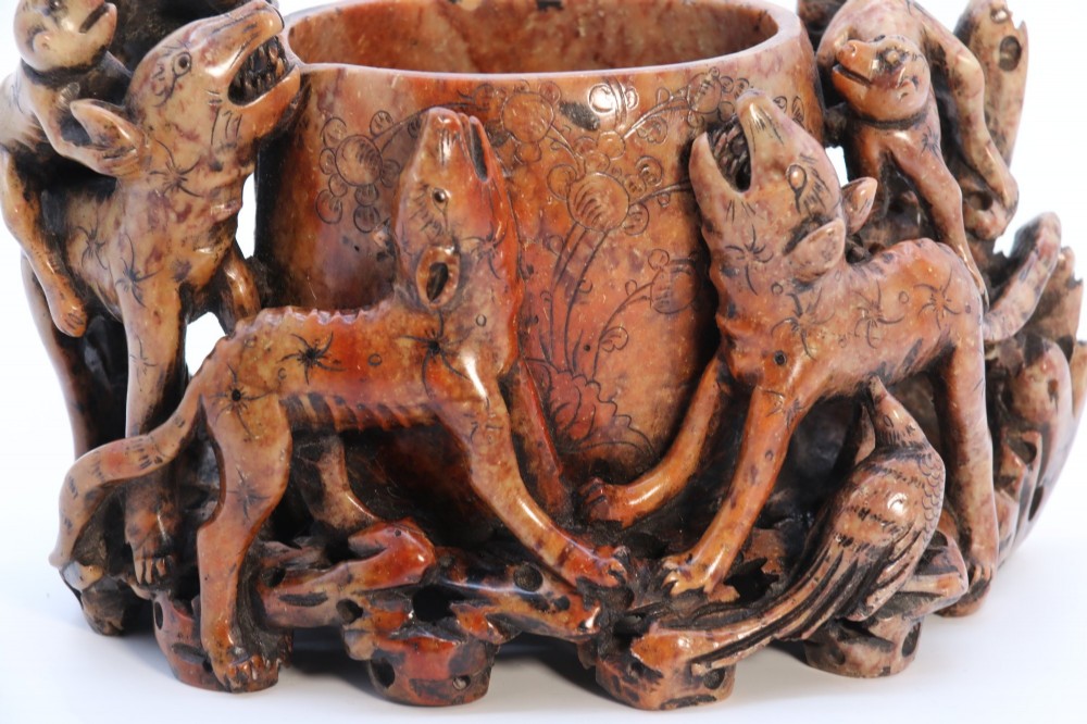 A cylindrical reddish-brown carved soapstone brush pot featuring sculpted animal figures in high relief surrounding an engraved vessel. View VIII