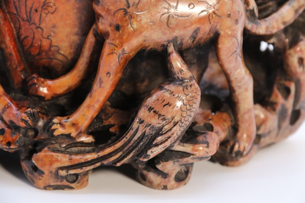 A cylindrical reddish-brown carved soapstone brush pot featuring sculpted animal figures in high relief surrounding an engraved vessel. View XI