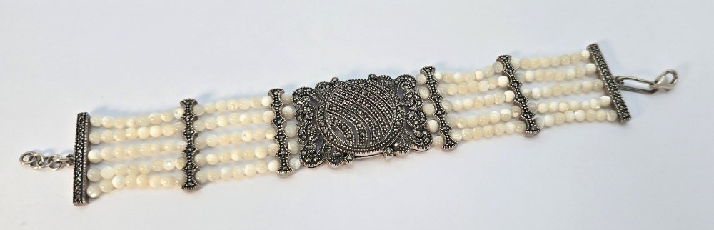 An Art Deco style multi-strand bracelet featuring white mother of pearl beads separated by intricate silver and marcasite decorative panels. View III