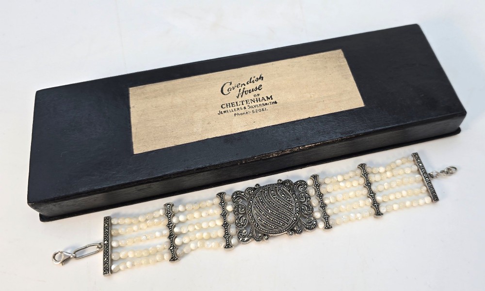 An Art Deco style multi-strand bracelet featuring white mother of pearl beads separated by intricate silver and marcasite decorative panels. View XIII