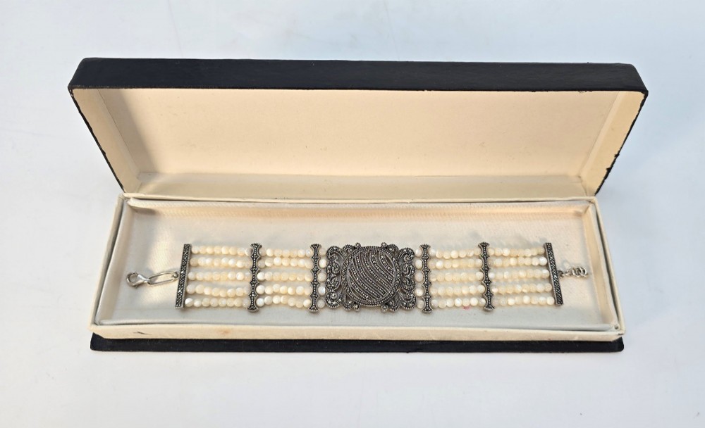 An Art Deco style multi-strand bracelet featuring white mother of pearl beads separated by intricate silver and marcasite decorative panels. View XIV