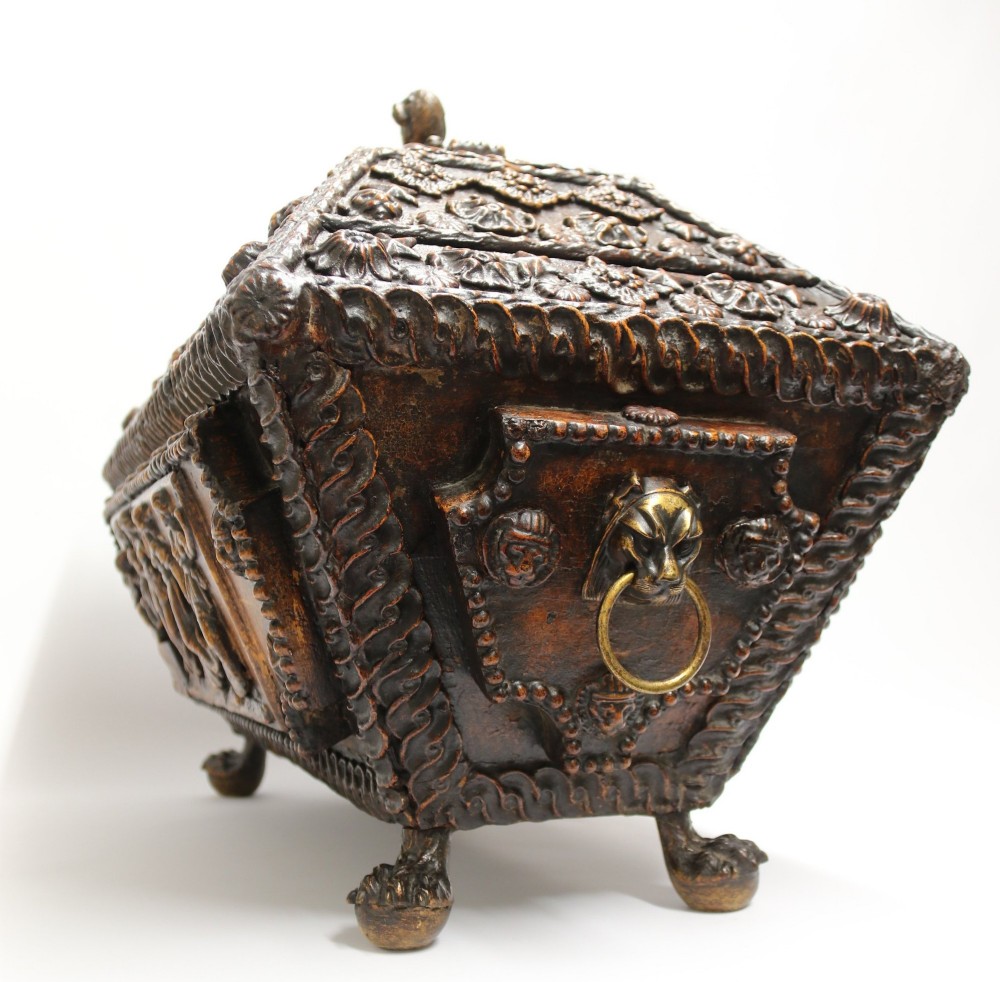 An early 19th-century sarcophagus-shaped gesso casket featuring raised classical relief panels, rope-twist borders, lion mask ring handles, and claw feet. View III