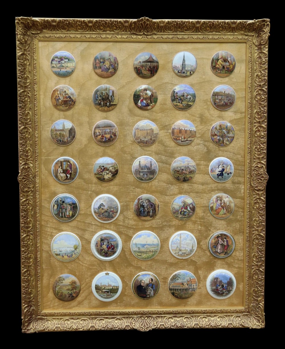 A large rectangular ornate gilt frame displaying thirty-five circular Victorian polychrome transfer-printed ceramic pot lids mounted in grid formation.