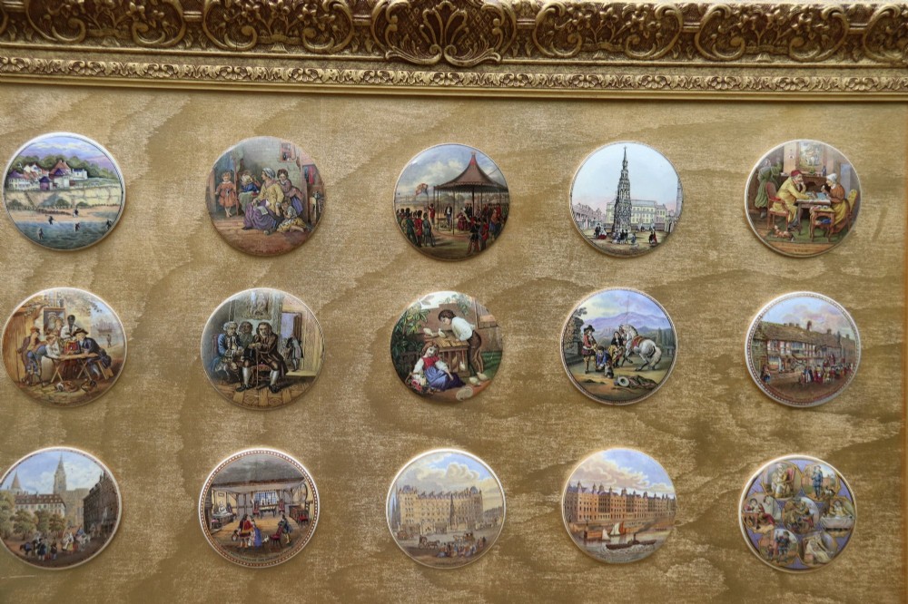 A large rectangular ornate gilt frame displaying thirty-five circular Victorian polychrome transfer-printed ceramic pot lids mounted in grid formation. View III