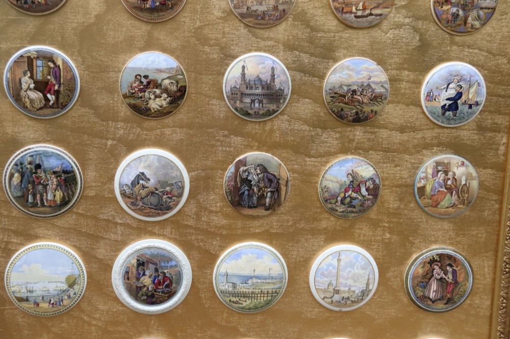 A large rectangular ornate gilt frame displaying thirty-five circular Victorian polychrome transfer-printed ceramic pot lids mounted in grid formation. View IV