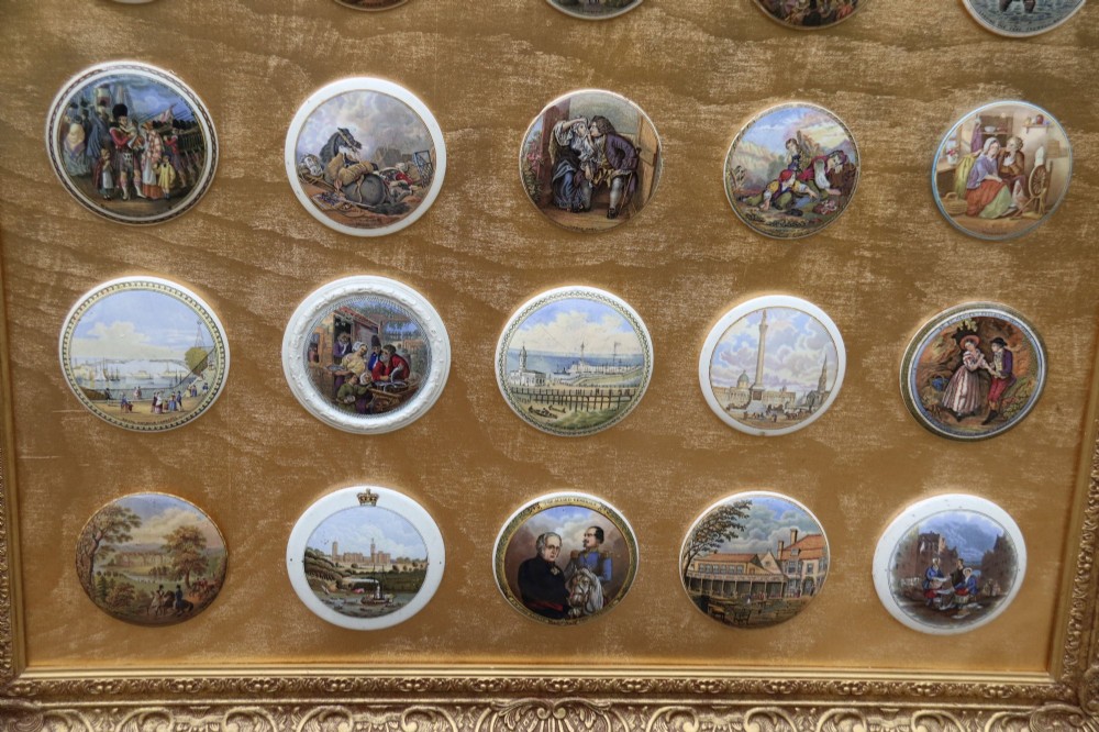 A large rectangular ornate gilt frame displaying thirty-five circular Victorian polychrome transfer-printed ceramic pot lids mounted in grid formation. View V