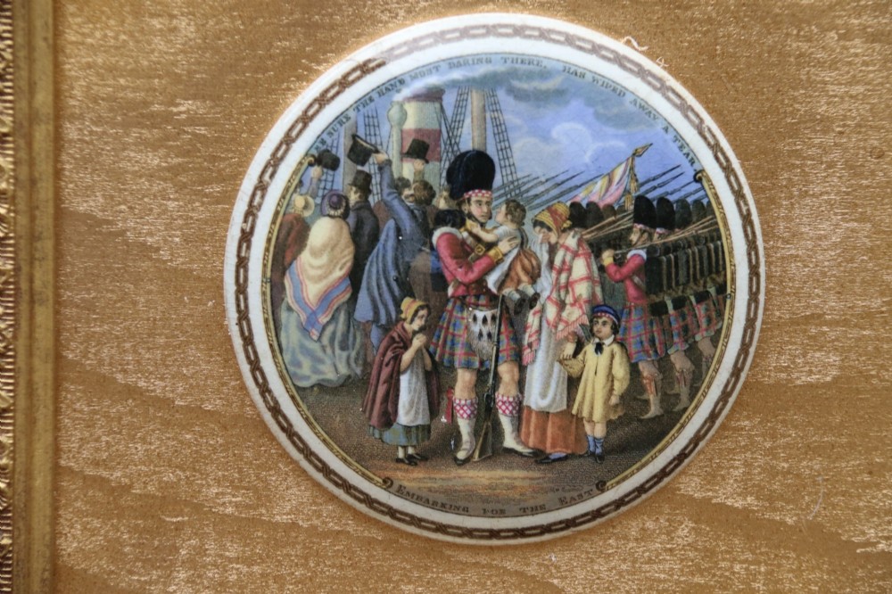 A large rectangular ornate gilt frame displaying thirty-five circular Victorian polychrome transfer-printed ceramic pot lids mounted in grid formation. View XII