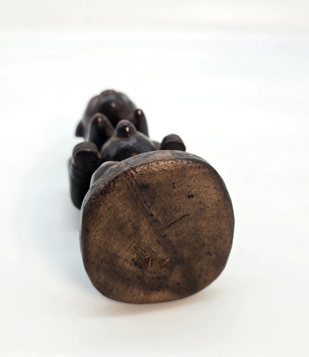 A dark brown hand-carved wooden figure depicting a kneeling female with a tall ridged headpiece and carved facial markings. View VIII