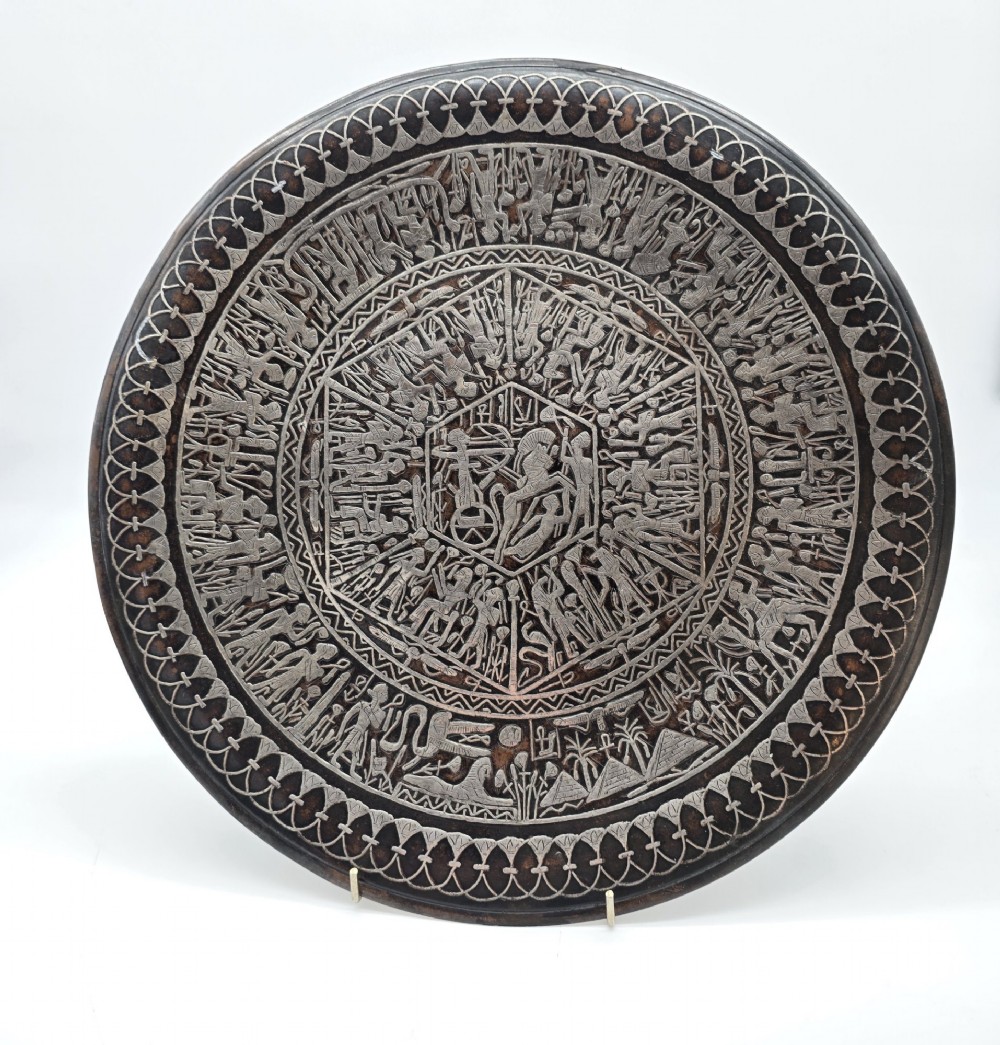 A circular antique Egyptian Cairo Ware wall charger made of dark copper intricately inlaid with silver depicting Pharaonic figures, pyramids, and hieroglyphs.