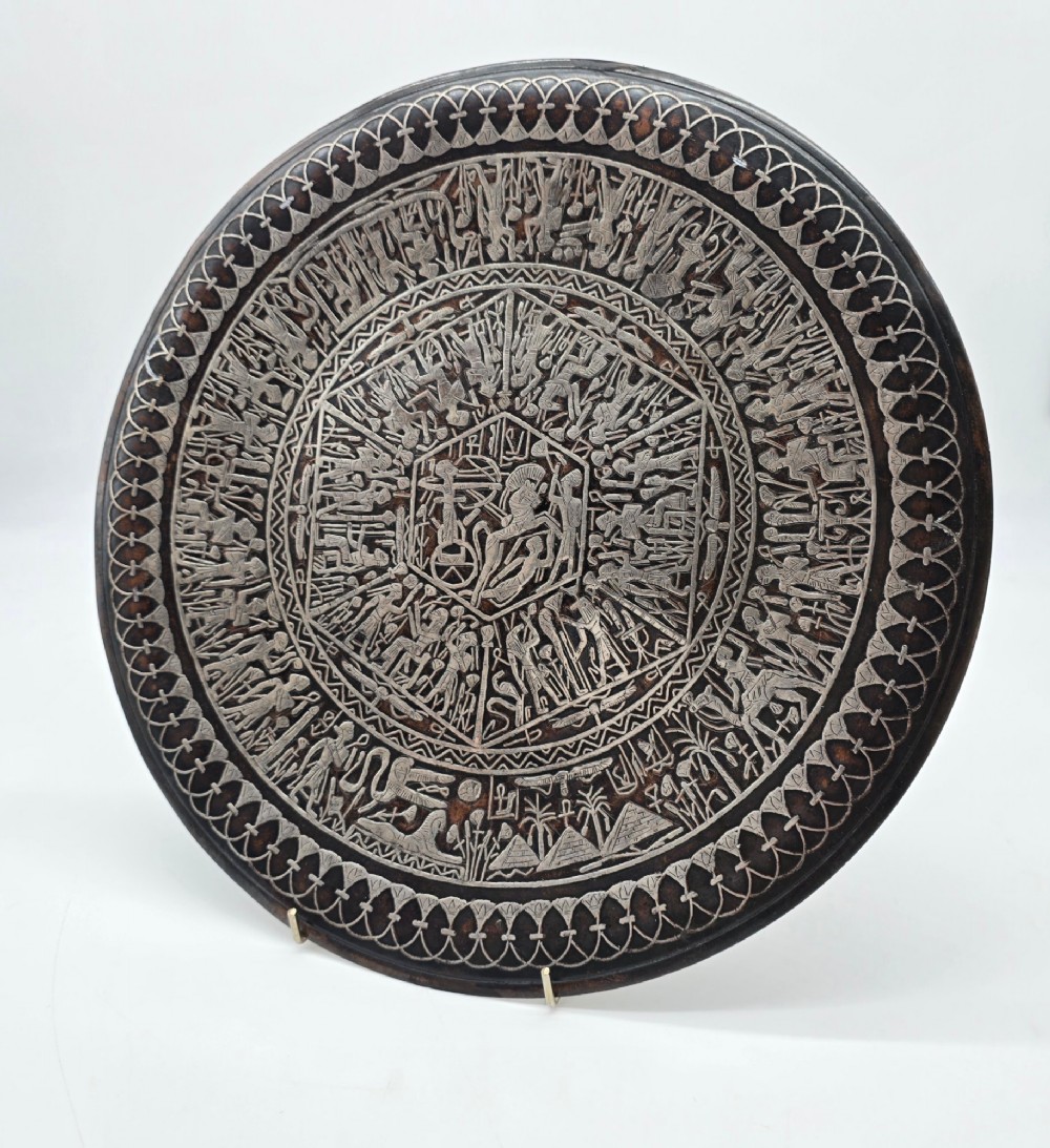 A circular antique Egyptian Cairo Ware wall charger made of dark copper intricately inlaid with silver depicting Pharaonic figures, pyramids, and hieroglyphs. View II