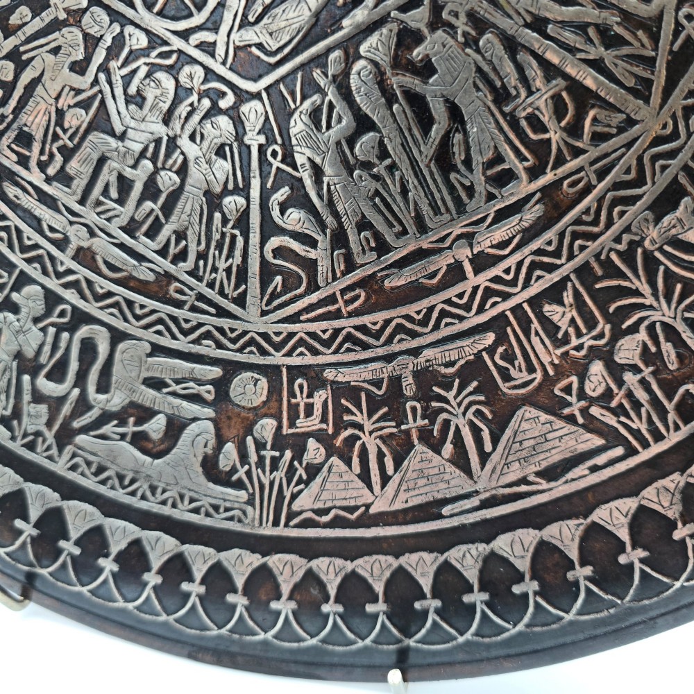 A circular antique Egyptian Cairo Ware wall charger made of dark copper intricately inlaid with silver depicting Pharaonic figures, pyramids, and hieroglyphs. View IX