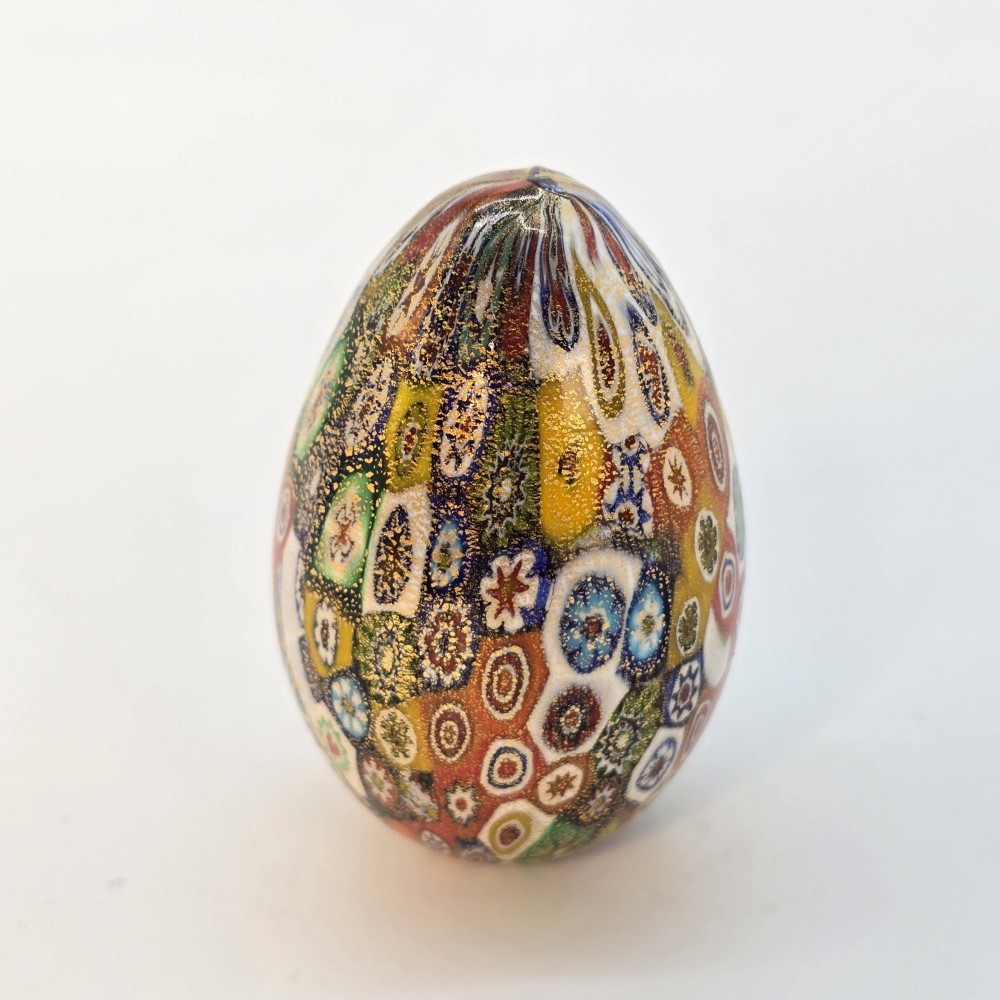 An egg-shaped Murano glass paperweight featuring colourful millefiori cane patterns and gold aventurine inclusions throughout. View III