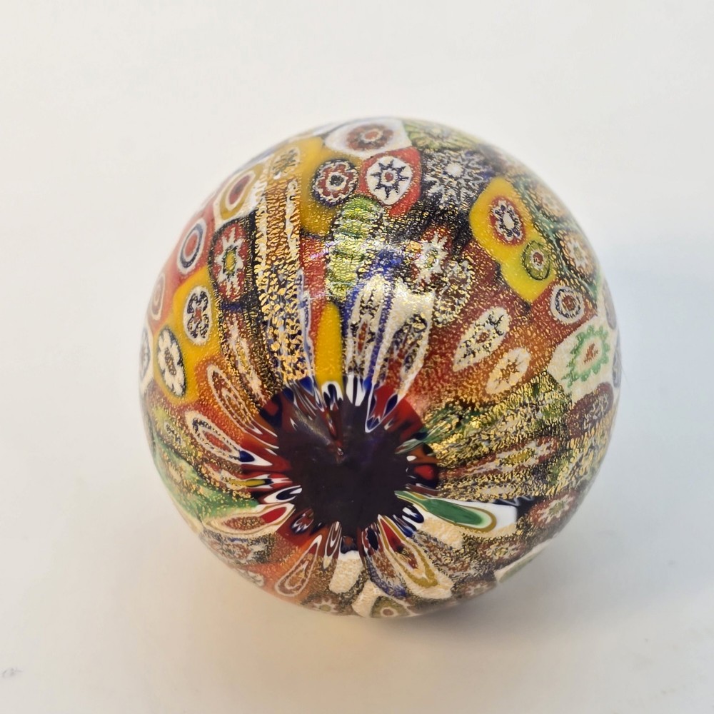 An egg-shaped Murano glass paperweight featuring colourful millefiori cane patterns and gold aventurine inclusions throughout. View IV